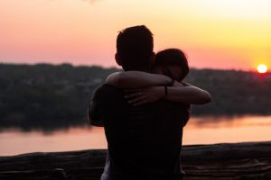 Military couple hugging in front of a sunset