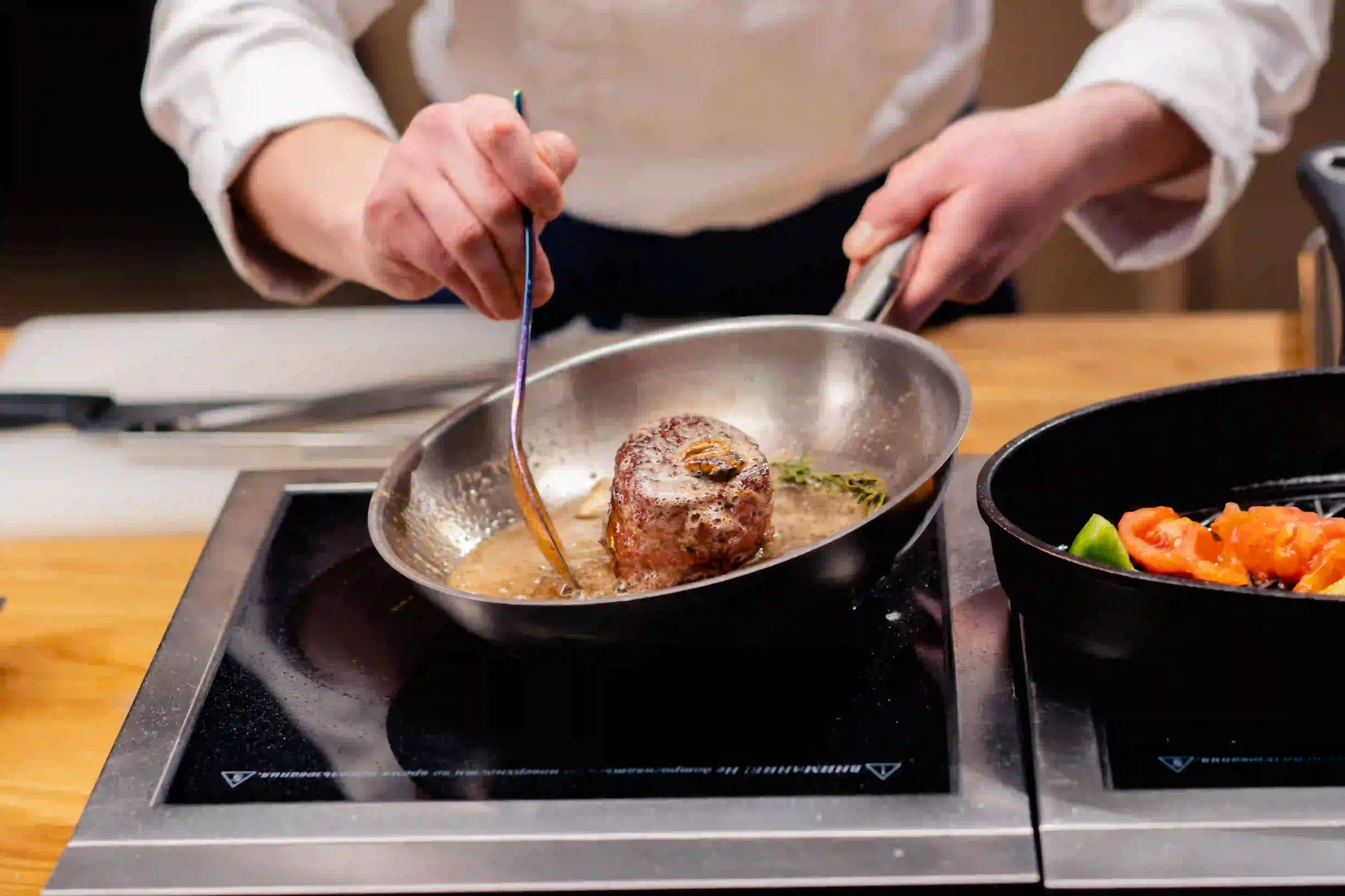 Restuarant chef bastes a filet mignon in butter.