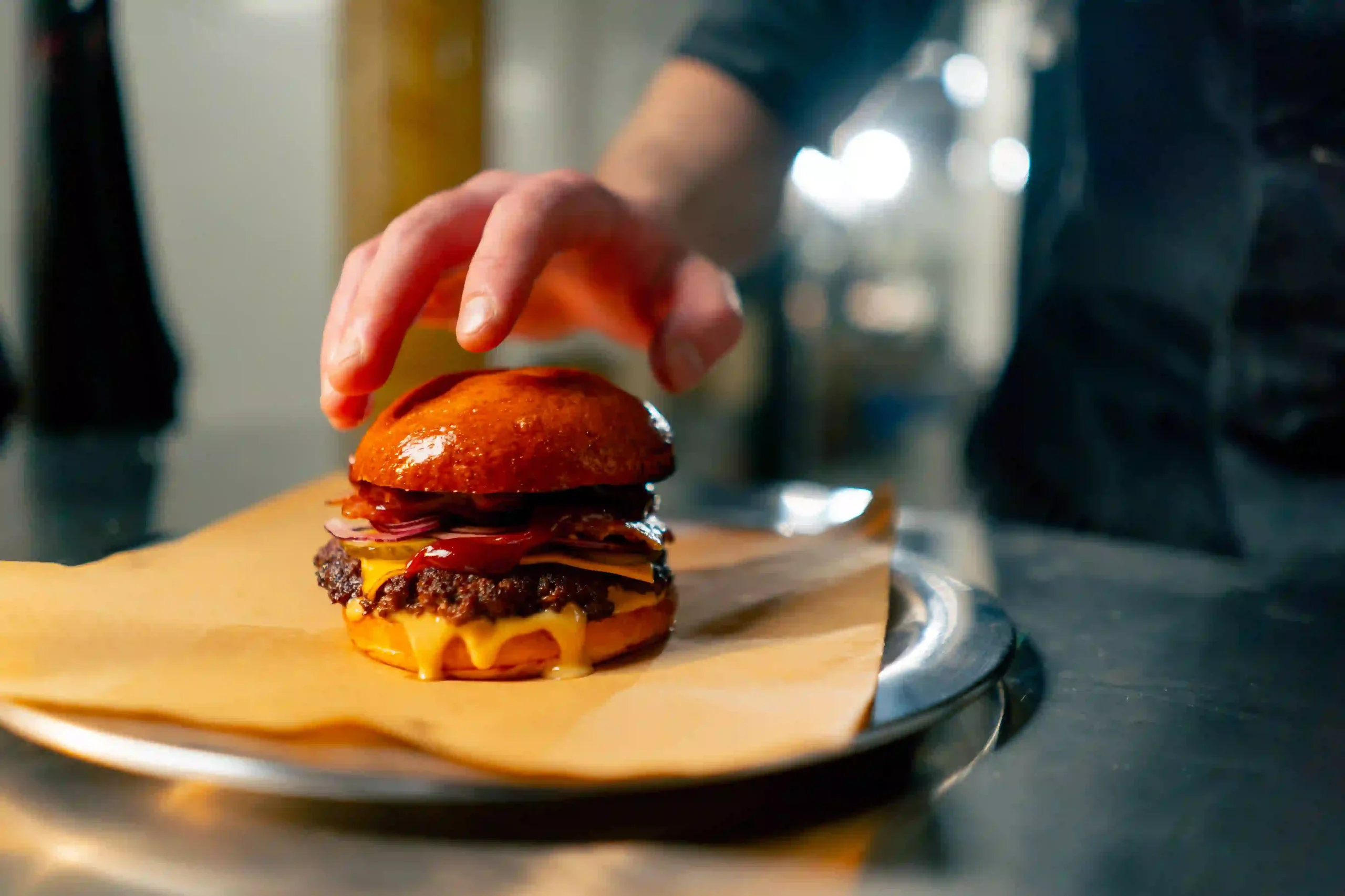 A restaurant chef puts the finishing touches on a hamburger. Washing pans after cooking a hamburger sends grease to a trap or interceptor.